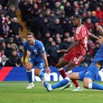 Liverpool striker Alexander Isak in red number 9 kit scores past Brighton defenders in blue kits ball heading towards net during Premier League match at Anfield  trybalnews