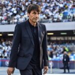 Antonio Conte wearing dark blue suit and black shirt walking on pitch at Stadio Diego Armando Maradona in Naples during Serie A match between Napoli and Udinese with fans in stands behind  trybalnews