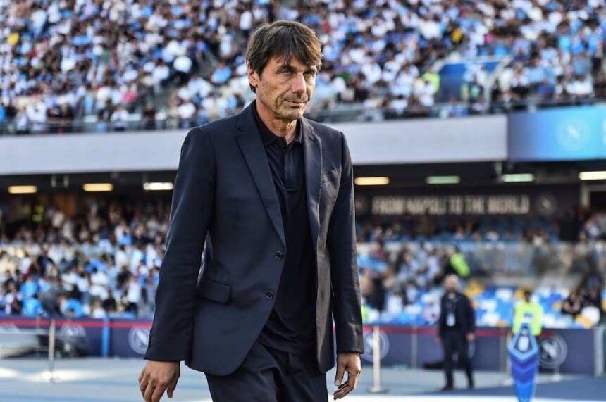 Antonio Conte wearing dark blue suit and black shirt walking on pitch at Stadio Diego Armando Maradona in Naples during Serie A match between Napoli and Udinese with fans in stands behind  trybalnews
