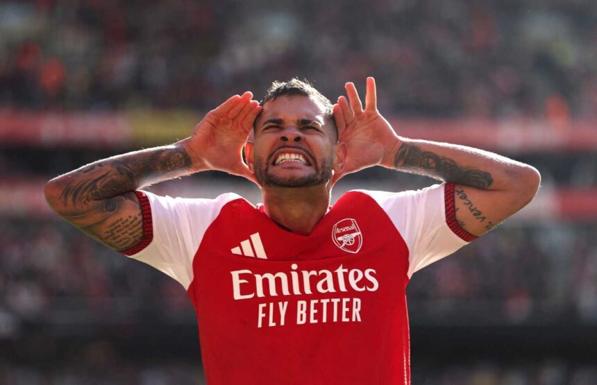 Arsenal midfielder Bruno Guimaraes celebrates with hands cupped around his ears after scoring during a Premier League match at Emirates Stadium He is wearing the red and white Arsenal home kit with visible arm tattoos  trybalnews