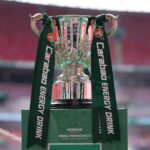 Silver Carabao Cup trophy with green Carabao Energy Drink ribbons on green plinth reading Arsenal v Manchester City Final 2026  trybalnews