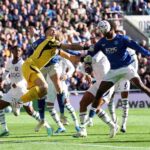 Chelsea goalkeeper Emiliano Martinez in yellow kit punches ball clear in aerial collision with Evertons Jarrad Branthwaite during Premier League 202627 match between Everton and Chelsea at Hill Dickinson Stadium Liverpool  trybalnews