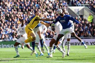 Chelsea goalkeeper Emiliano Martinez in yellow kit punches ball clear in aerial collision with Evertons Jarrad Branthwaite during Premier League 202627 match between Everton and Chelsea at Hill Dickinson Stadium Liverpool  trybalnews