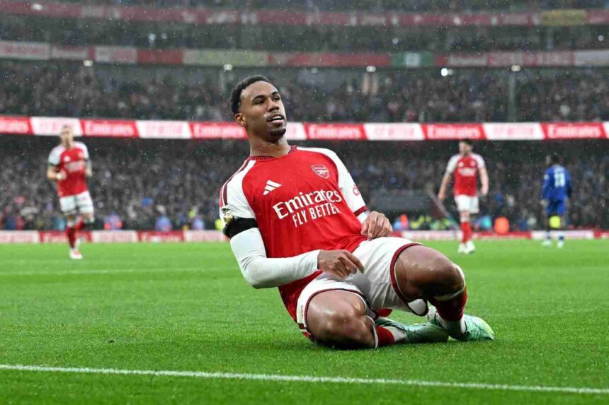 Arsenal defender Gabriel in red Emirates shirt sliding on knees in rain celebrating goal at Emirates Stadium teammates running behind him during Premier League match against Everton  trybalnews