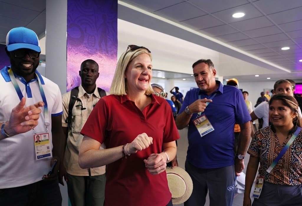IOC President Kirsty Coventry wearing a red polo shirt reacts with a smile during her visit to the Olympic Village in Diamniadio ahead of the Dakar 2026 Youth Olympic Games surrounded by officials  trybalnews