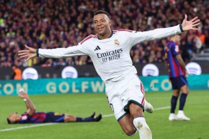 Real Madrid forward Kylian Mbappe in white kit with arms outstretched celebrating goal against Barcelona in El Clasico at Camp Nou