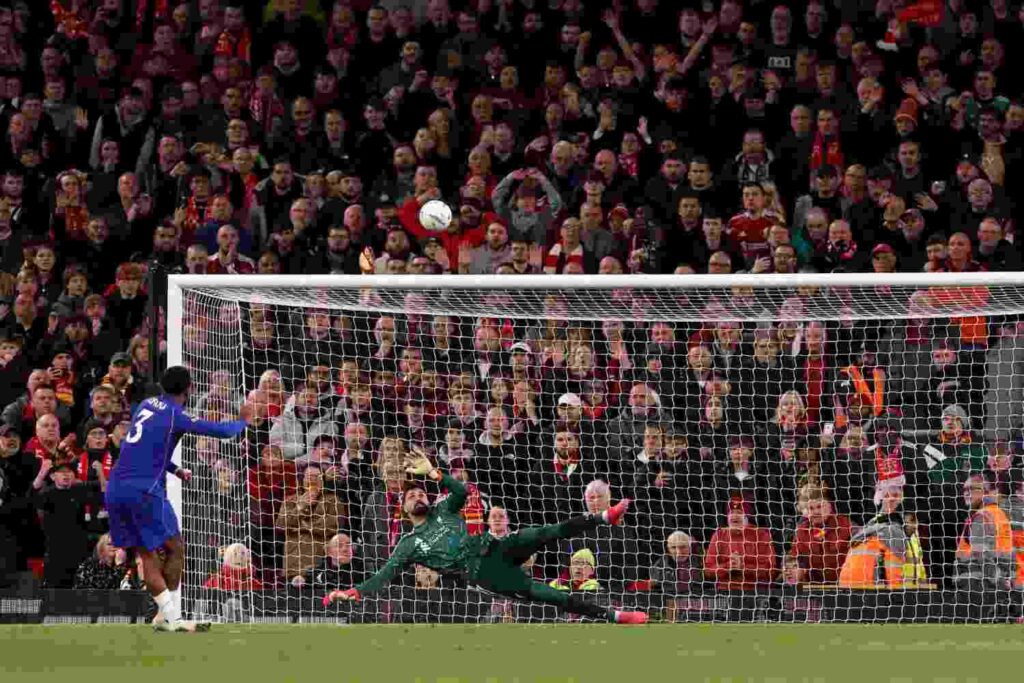 Liverpool v Chelsea Trybal News Chelsea player in blue kit with number 3 kicking ball over crossbar while Liverpool goalkeeper in green dives crowd in background reacting during penalty shootout trybalnews