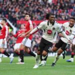 AFC Bournemouth player Rayan in white and black kit smiling and celebrating after scoring against Manchester United teammate chasing to celebrate Manchester United players looking dejected at Old Trafford  trybalnews