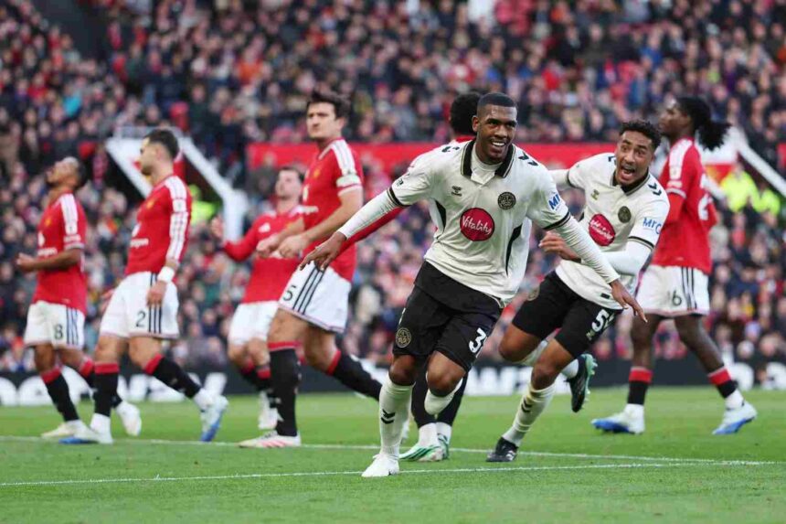 AFC Bournemouth player Rayan in white and black kit smiling and celebrating after scoring against Manchester United teammate chasing to celebrate Manchester United players looking dejected at Old Trafford  trybalnews