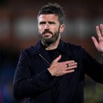 Michael Carrick wearing black jacket with hand on chest and other hand raised apologising to Manchester United supporters after 4 1 Champions League loss to Como 1907 at Giuseppe Sinigaglia Stadium  trybalnews