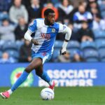 Ryan Alebiosu of Blackburn Rovers in blue and white halved kit dribbling ball on pitch wearing pink boots and white wrist bandage during Championship match at Ewood Park  trybalnews