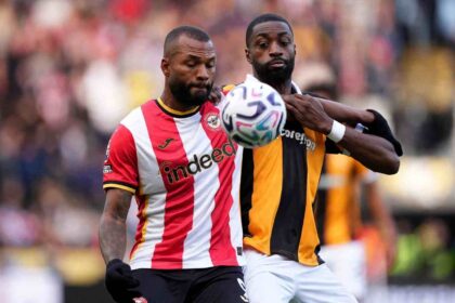 Brentford striker Igor Thiago in red and white striped shirt battling with Hull City defender Semi Ajayi in orange and black striped shirt for aerial ball during Premier League match at MKM Stadium