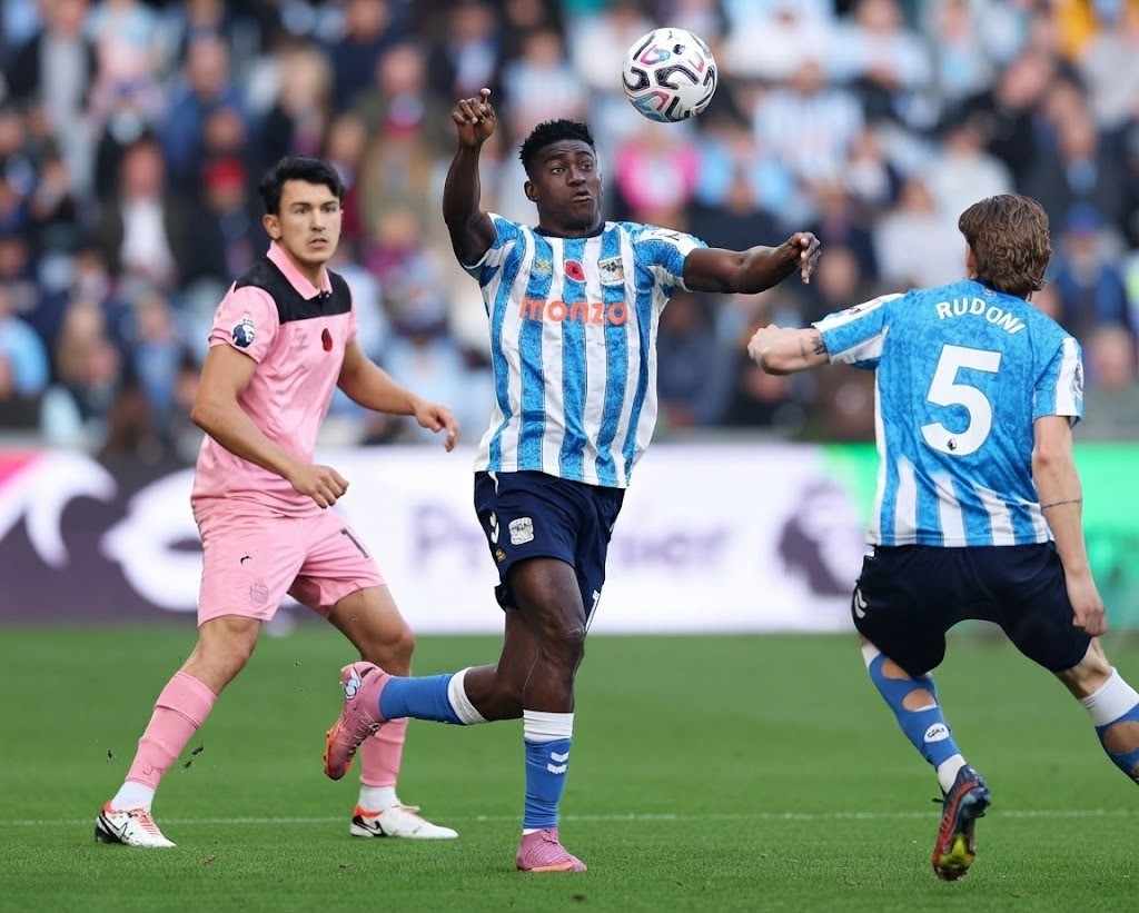 Taiwo Awoniyi Trybal News Coventry City striker Taiwo Awoniyi wearing the blue and white striped No 9 shirt jumps to head the ball during the Premier League match against Sunderland with teammate Jack Rudoni and a Sunderland player in pink nearby trybalnews