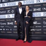 Victor Osimhen in a black tuxedo with his girlfriend Stephanie in a black evening dress posing on the red carpet at the AIC Gran Galà del Calcio Awards in Milan  trybalnews