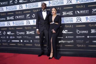 Victor Osimhen in a black tuxedo with his girlfriend Stephanie in a black evening dress posing on the red carpet at the AIC Gran Galà del Calcio Awards in Milan  trybalnews